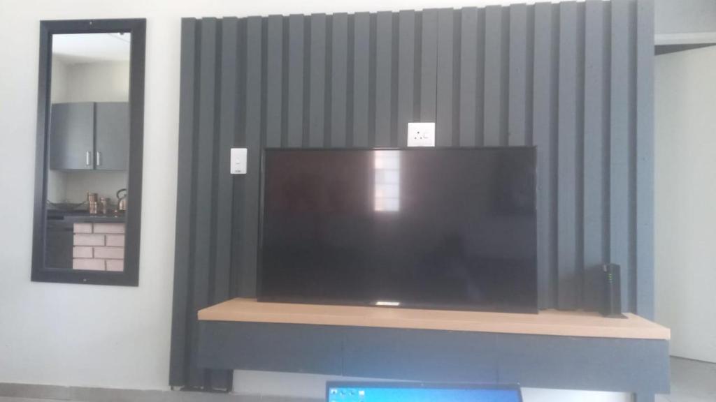 a large flat screen tv on a shelf in a room at Waterfall Ridge Apartments - Kick back and Relax in Midrand