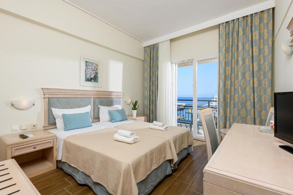 ein Hotelzimmer mit einem Bett und einem Balkon in der Unterkunft Hotel Timoleon in Limenas