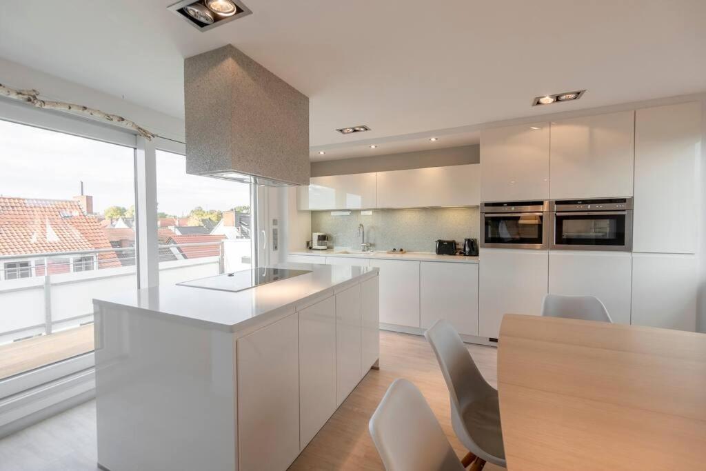 een keuken met witte kasten en een tafel met stoelen bij Luxus 5-Sterne Appartement für 4 in Bremen