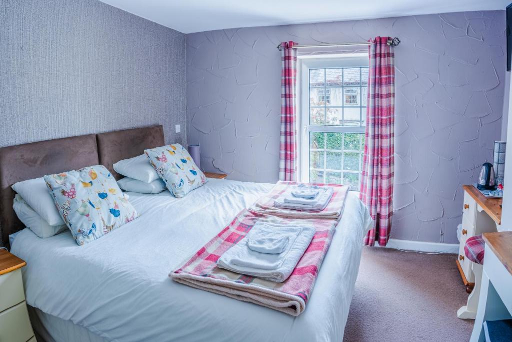 ein Schlafzimmer mit einem Bett mit Handtüchern und einem Fenster in der Unterkunft The Cock Hotel in Bronllys