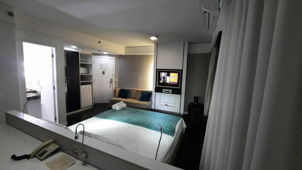 um quarto com uma cama grande e um espelho em Flat Hotel av Macuco São Paulo Ibirapuera UH-2710 em São Paulo