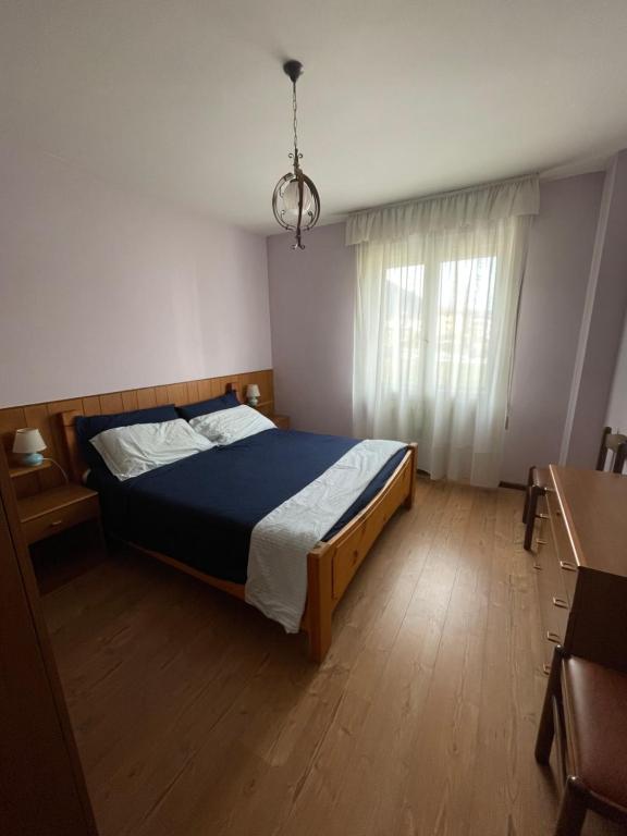 - une chambre avec un lit doté d'une couette bleue et d'une fenêtre dans l'établissement Casa Anna - Andalo centrale sugli impianti da sci, à Andalo