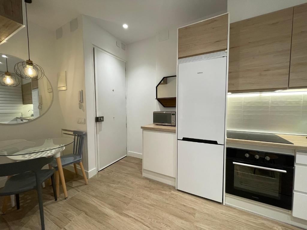 a kitchen with a table and a white refrigerator at Cozy apartment in Plaza España /Gran Vía in Madrid