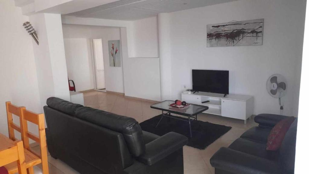 uma sala de estar com um sofá de couro preto e uma mesa em Stay at Kety`s II em Praia