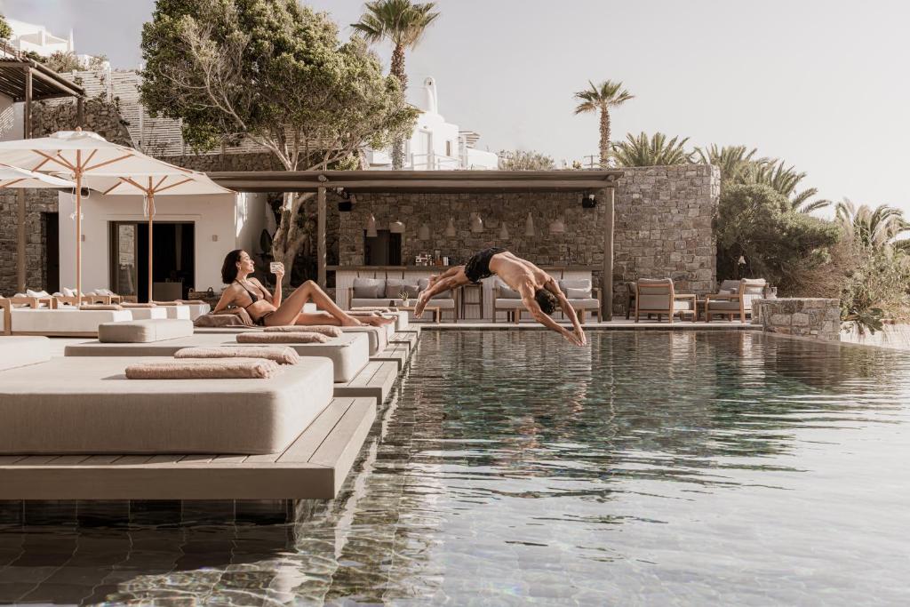 um homem a saltar para uma piscina num resort em Enigma Mykonos Hideaway Suites em Ornos