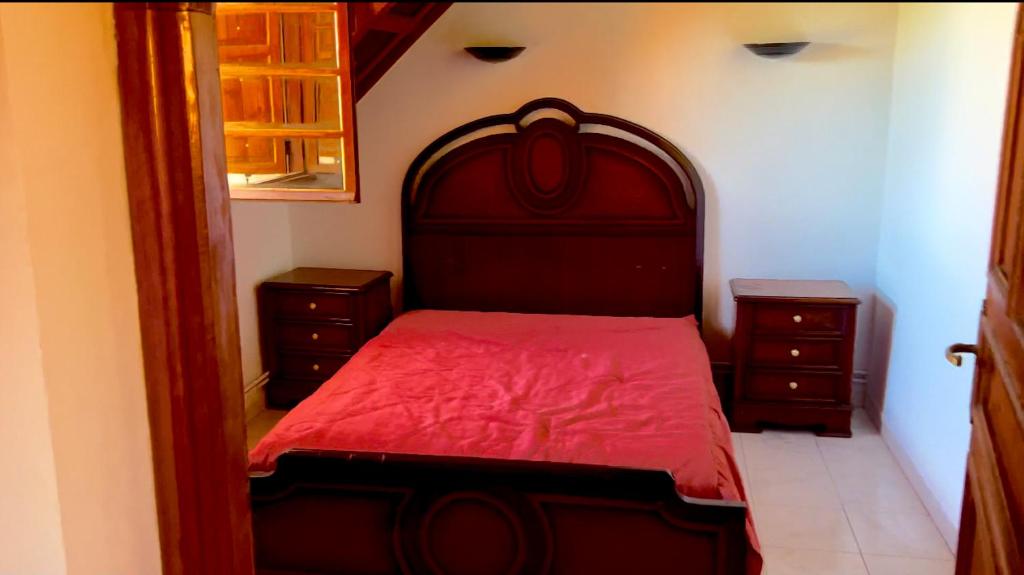 a bedroom with a red bed and two dressers at Villa jouhara in Ifrane