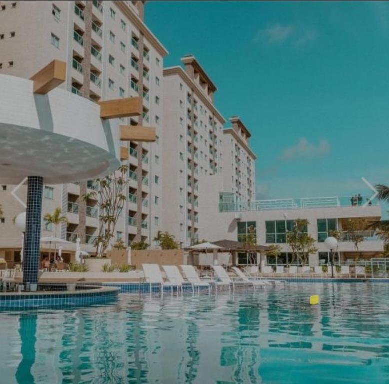 a swimming pool with chairs and a large building at Salinas Gav Resort in Salinópolis