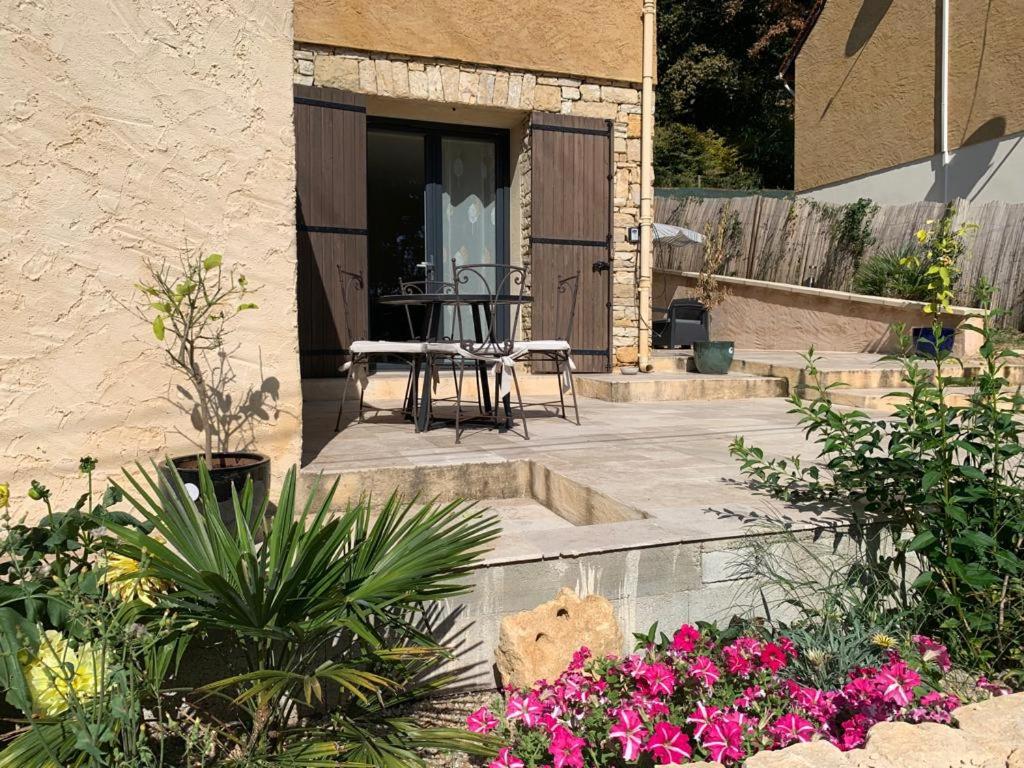 um pátio com uma mesa, cadeiras e flores em Chez ALYS - Appartement Sarlat em Sarlat-la-Canéda