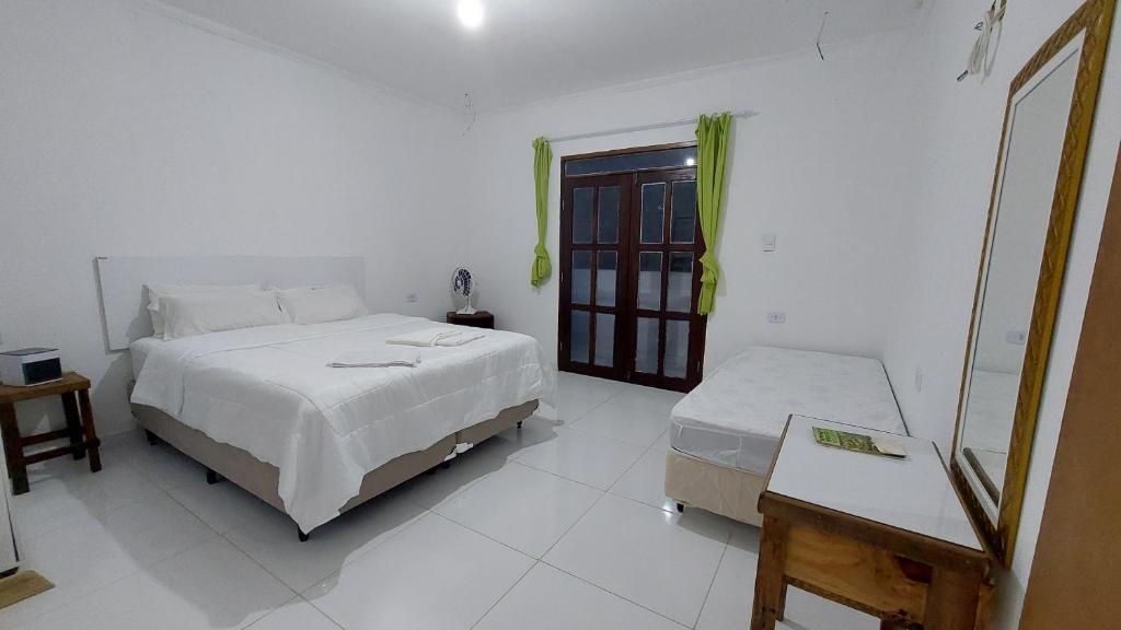 Habitación blanca con cama y ventana en Residencial Maria de Lourdes, en Ibicoara