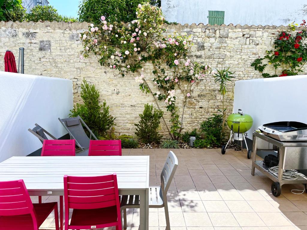 un patio con sillas rojas, una mesa y una parrilla en Maison Telline, en Saint-Martin-de-Ré