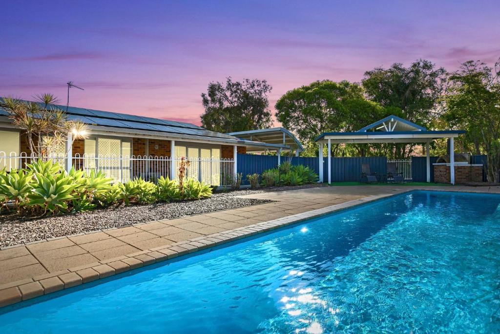 a swimming pool in front of a house at WhiteSands Beachouse in Urangan