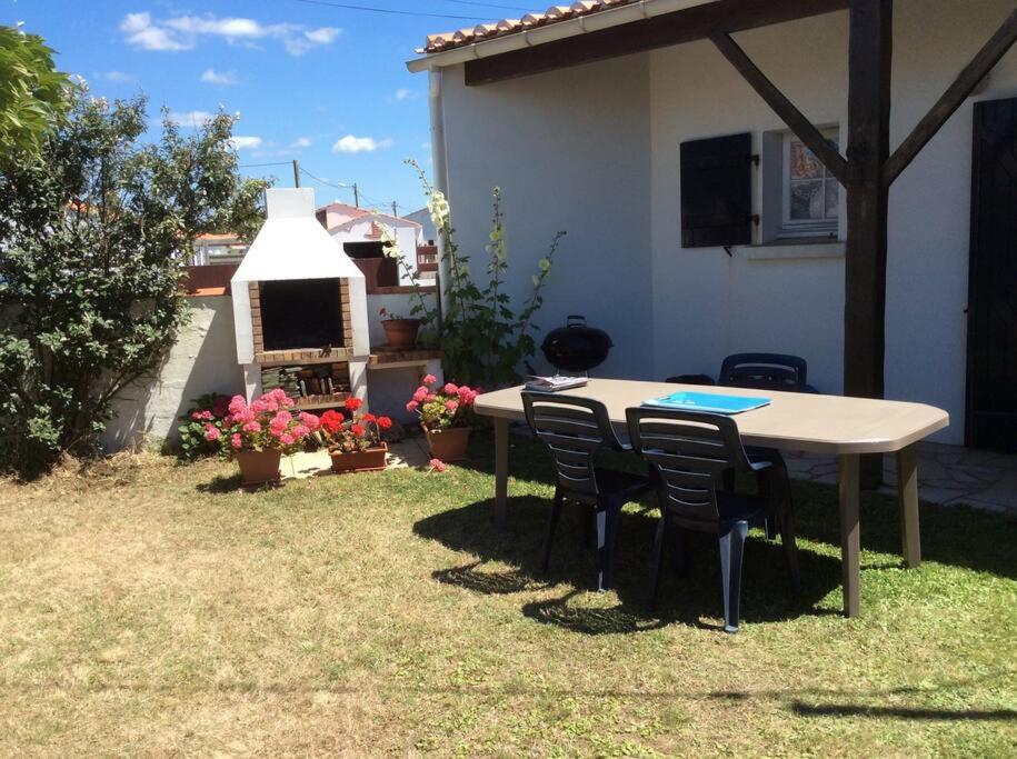 una mesa y sillas en el patio trasero de una casa en maison de vacances en bord de mer, en Saint-Hilaire-de-Riez