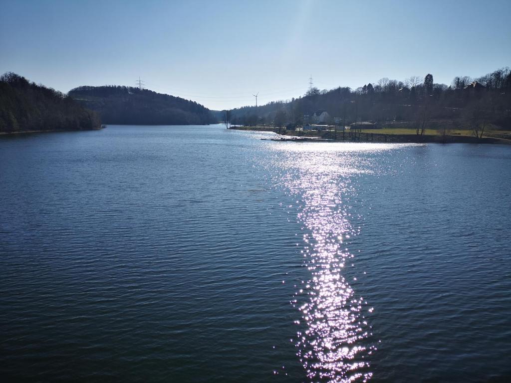 a large lake with the sun reflecting on the water at Hotel Radevormwald in Radevormwald