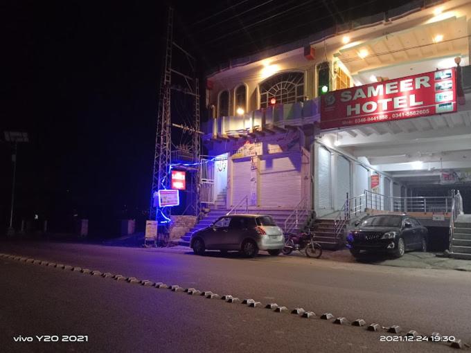 two cars parked in front of a garage at night at Sameer Hotel in Swat