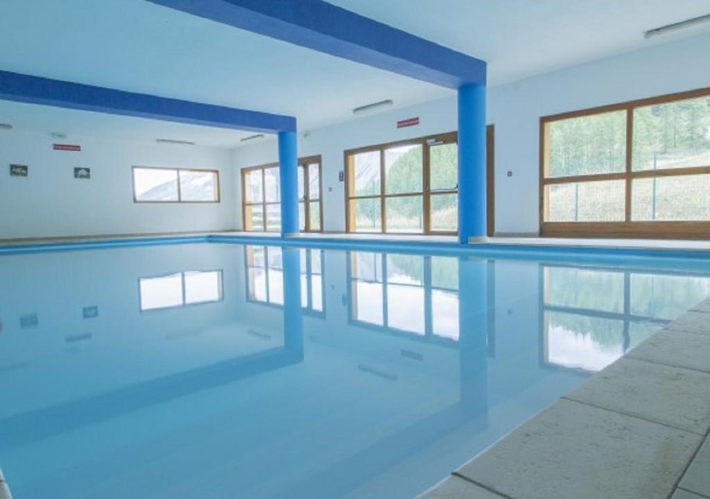 une piscine vide aux murs bleus et aux fenêtres dans l'établissement Superbe appartement en résidence avec piscine LES ORRES 1800, aux Orres