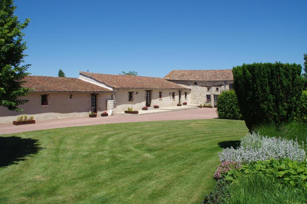 una casa con un césped verde delante de ella en Manoir Les Touches 