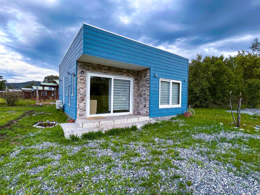 ein kleines blaues Haus auf einem Blumenfeld in der Unterkunft Cabañas Maravillas de Quetroleufu in Pucón