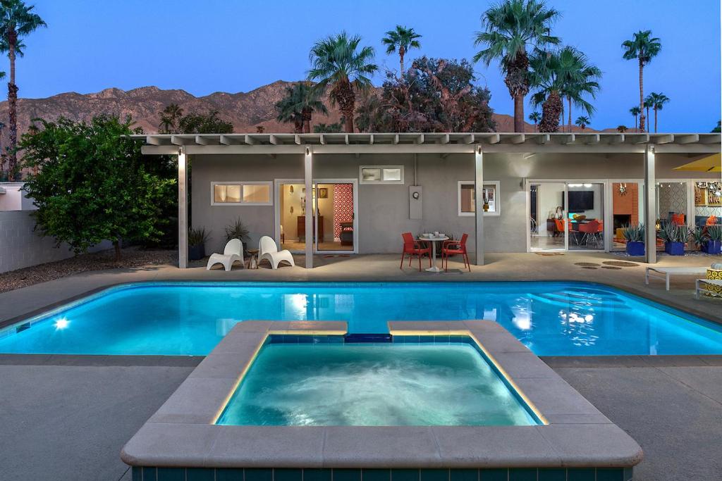 a swimming pool in front of a house at On The Rox- Luxury Refreshing Mid-Century Mod- Pool, Spa, Firepit, Outdoor Kitchen & More in Palm Springs