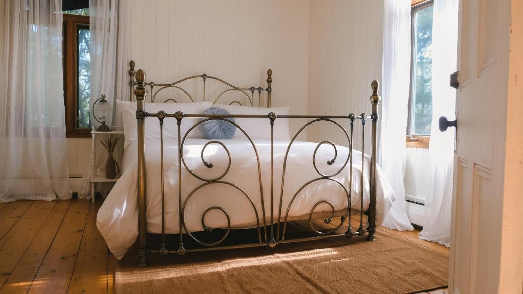 uma cama de metal num quarto com piso de madeira em Auberge des Korrigans em Stoneham