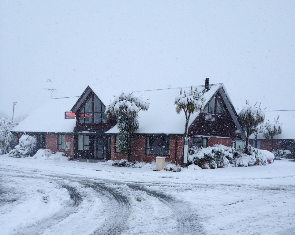 a house covered in snow with a dirt road at Snow Denn Lodge in Methven