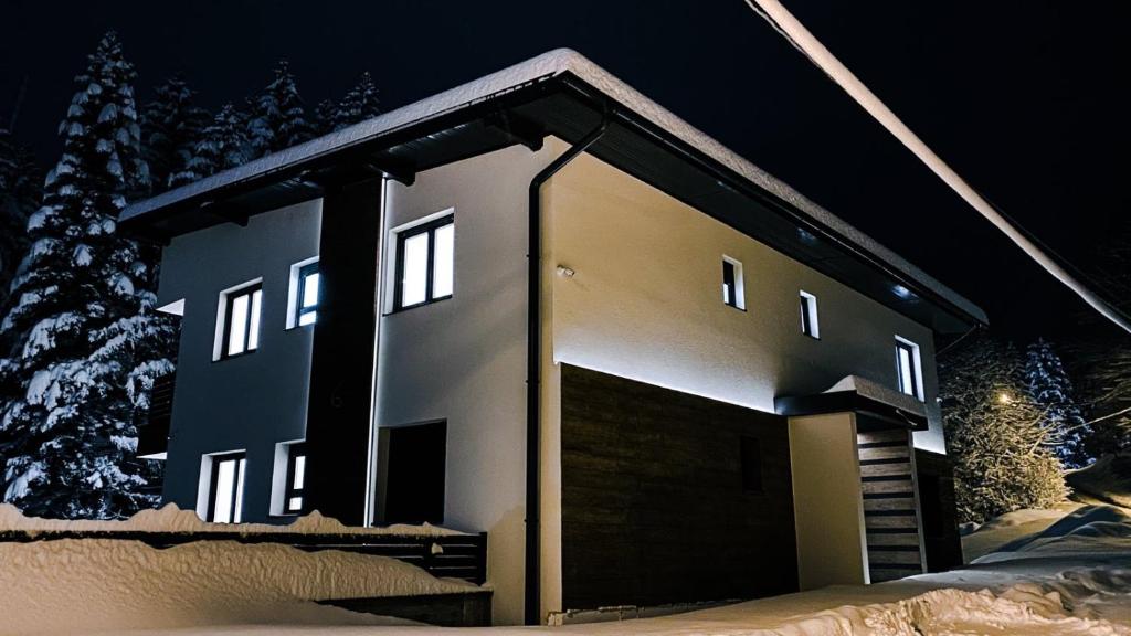 a house with a garage in the snow at night at Apartmani Berg in Pale