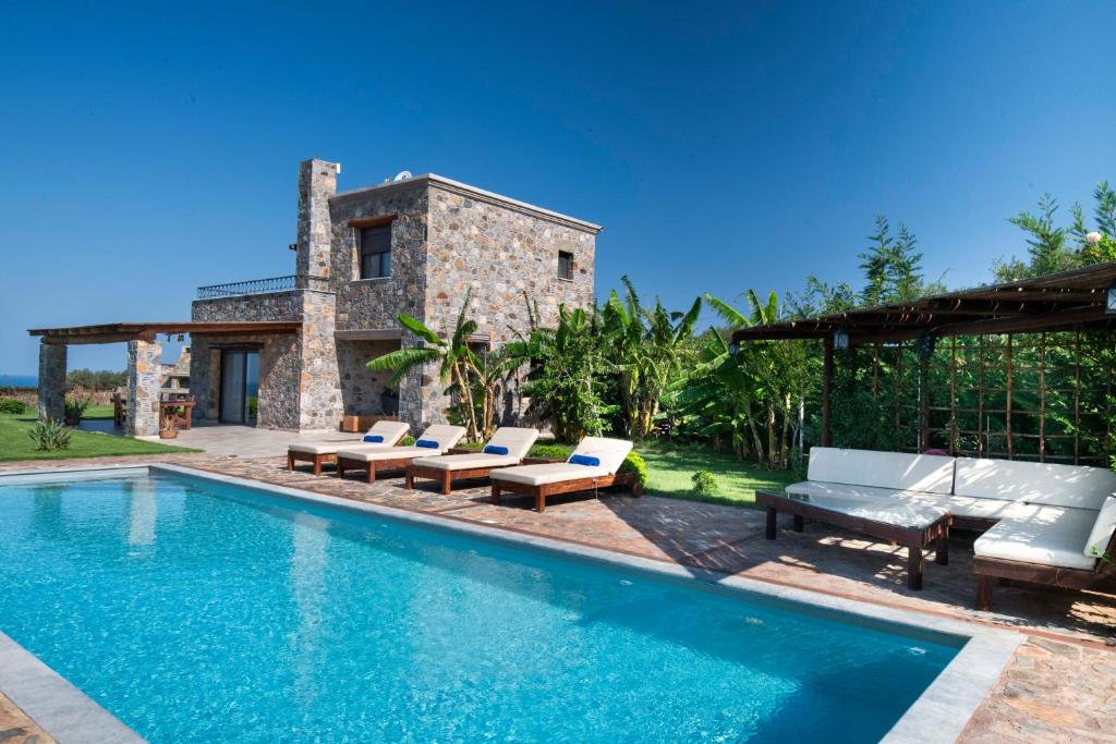 a swimming pool with lounge chairs and a house at Villa Kore Elafonissi in Ãyios FÃ³tios
