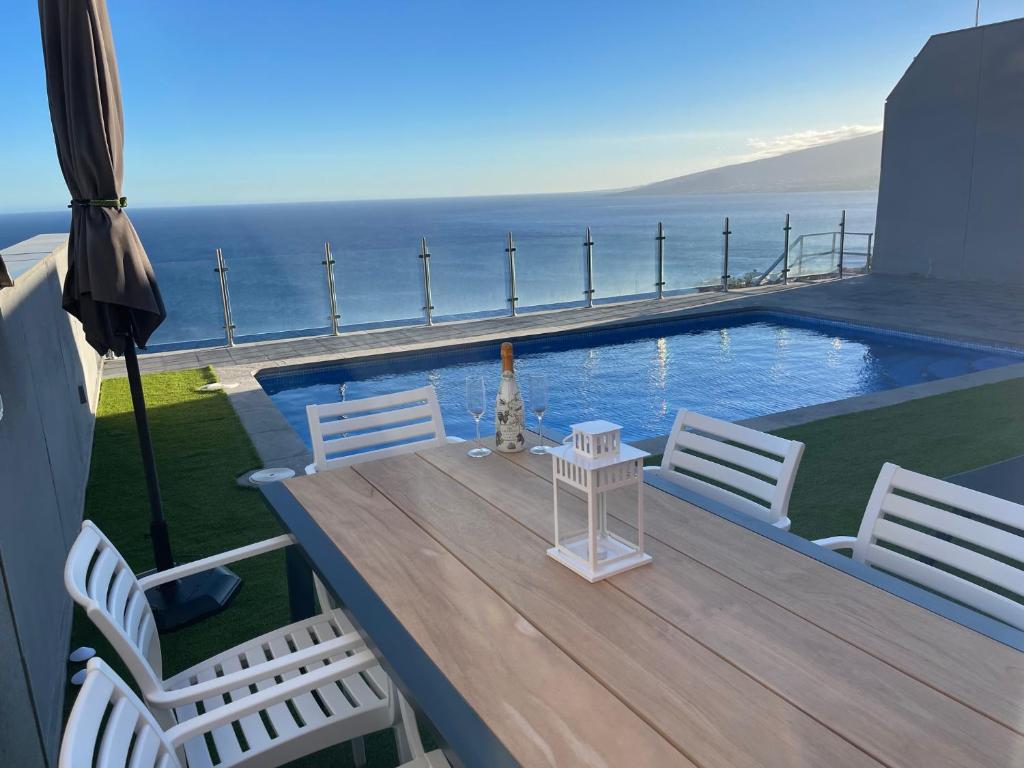 eine Terrasse mit weißen Stühlen und einem Pool in der Unterkunft Villa Costa in Santa Cruz de Tenerife