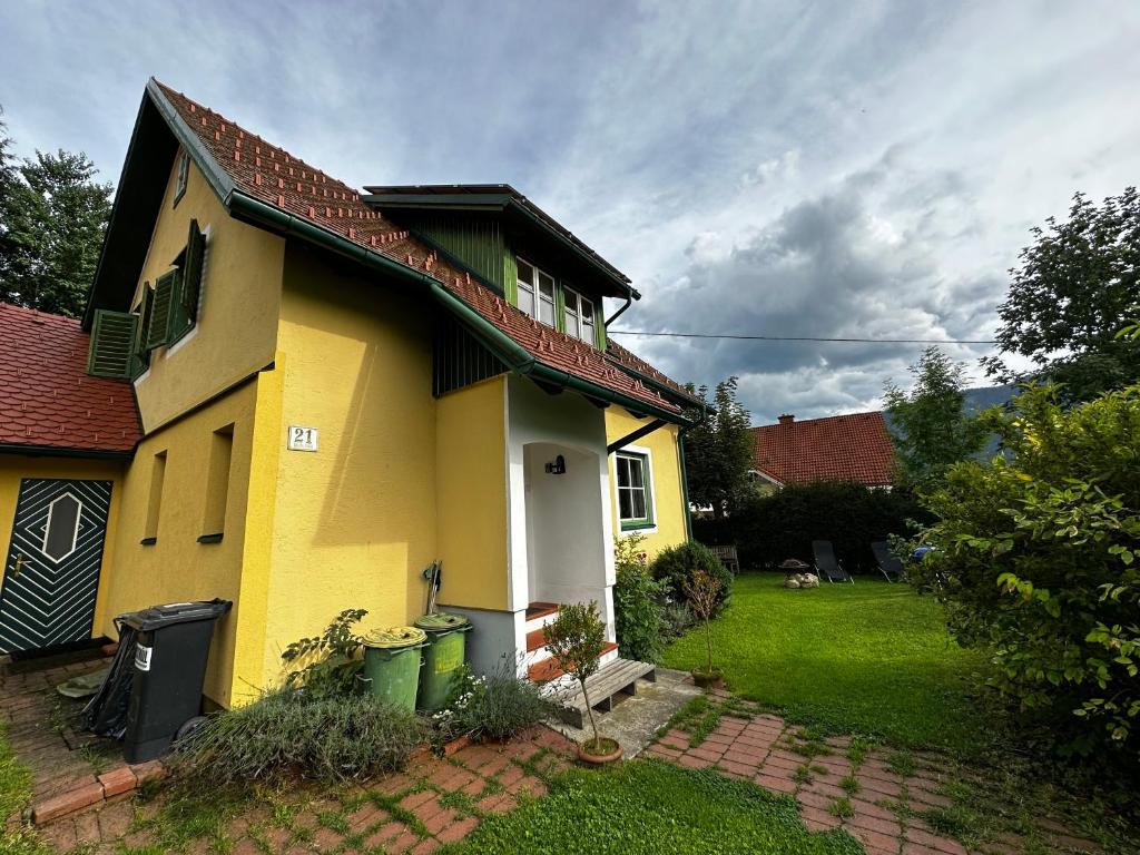żółty dom z dwoma zielonymi koszami na śmieci w ogrodzie w obiekcie Ferienhaus Prettenthaler w mieście Gaal