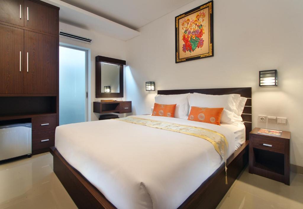 um quarto com uma grande cama branca com almofadas laranja em Lotus Tirta Seminyak em Seminyak
