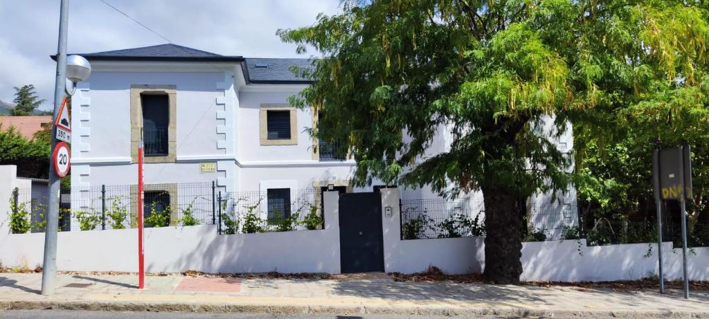 een wit huis met een boom ervoor bij La Casita de Peter in El Escorial