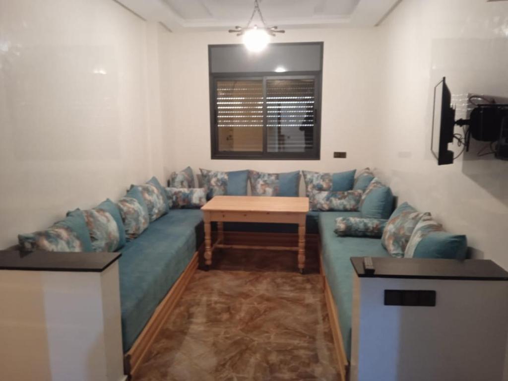 een woonkamer met een blauwe bank en een tafel bij Appartement familial 1 in Oualidia