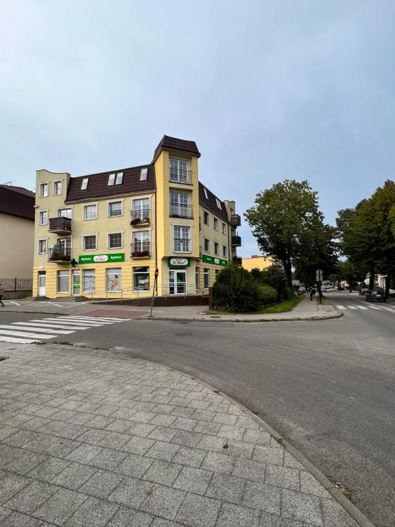 an empty street with a yellow building on the corner at Apartament Puck Przestronny i Nowoczesny in Puck
