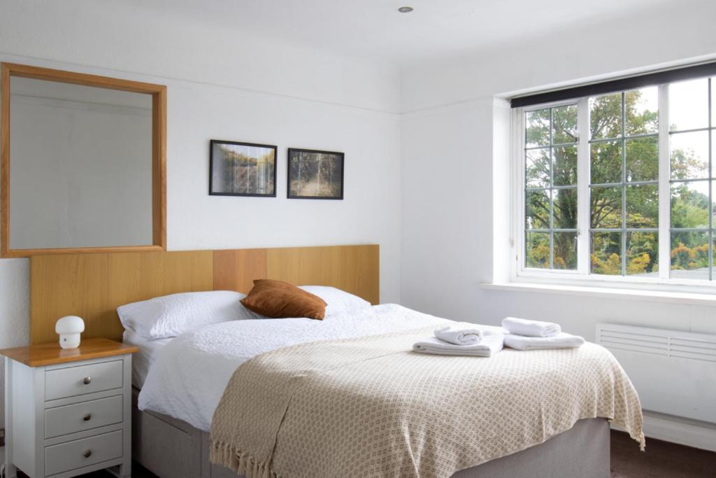 a white bedroom with a bed and a window at One-Bedroom flat in Cheam Village in Cheam