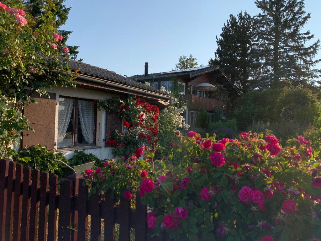 a house with flowers in front of a fence at Jolie chambre dans chalet in Le Vaud