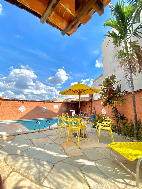 a patio with yellow tables and chairs and a pool at Vila Vitória Pousada in Pirenópolis