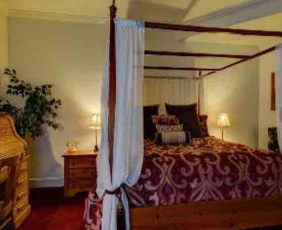 1 dormitorio con 1 cama grande con dosel en The Currier Inn, en Greeley