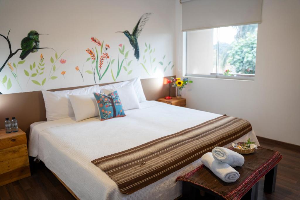 a bedroom with a large white bed with towels on a table at Casa Boutique QX- Pachacamac in Pachacamac