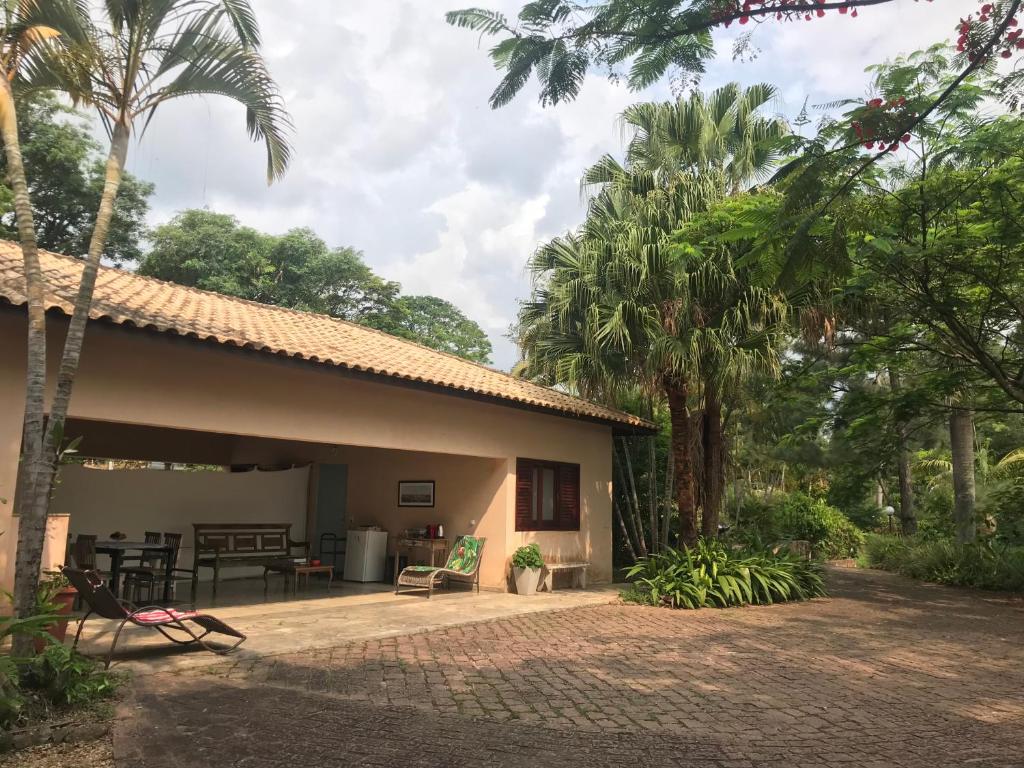 a house with a patio and palm trees at Loft em chácara Espírito Santo in Espirito Santo Do Pinhal