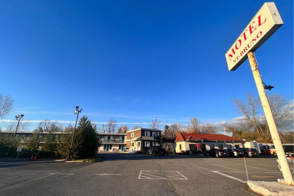 Motel Saint Bruno في Saint-Bruno-de-Montarville: موقف سيارات فارغ مع وجود علامة غلة على شارع