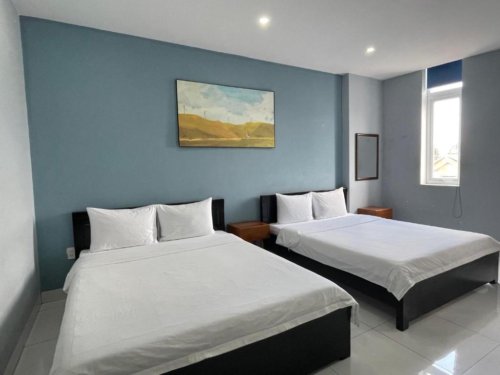 two beds in a room with blue walls at An Nhiên Hotel in Tây Ninh