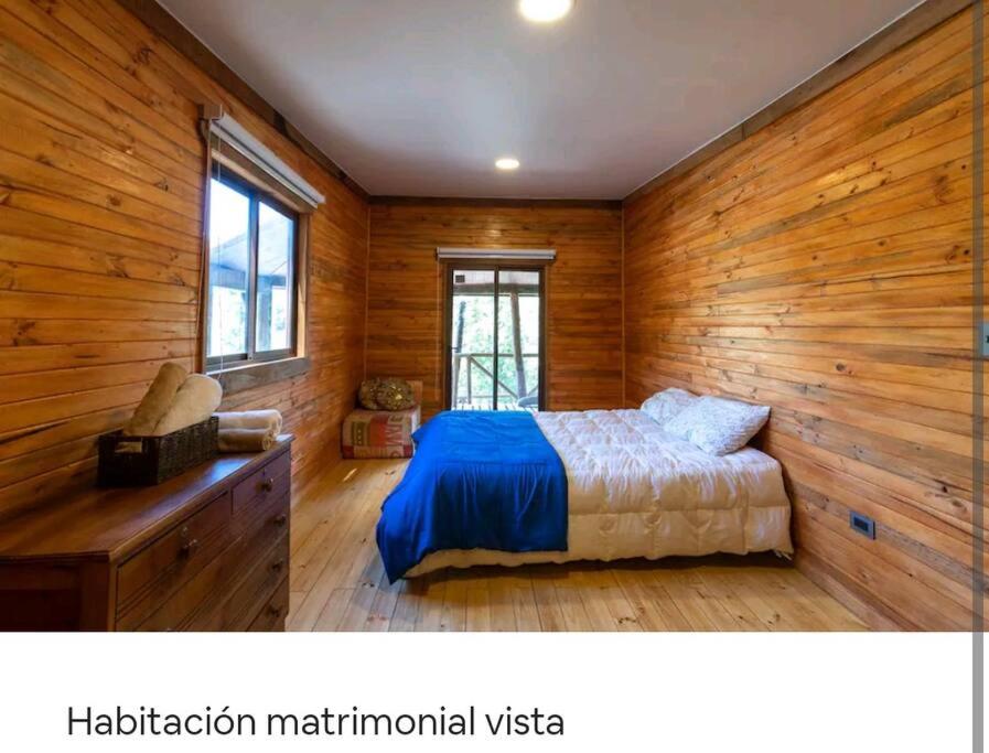 1 dormitorio con paredes de madera y 1 cama en una habitación en Guariliwe Ecolodge and Wines, en Coelemu