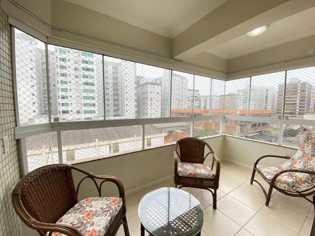 einen Balkon mit Stühlen, einem Tisch und Fenstern in der Unterkunft Apartamento capão da canoa in Capão da Canoa