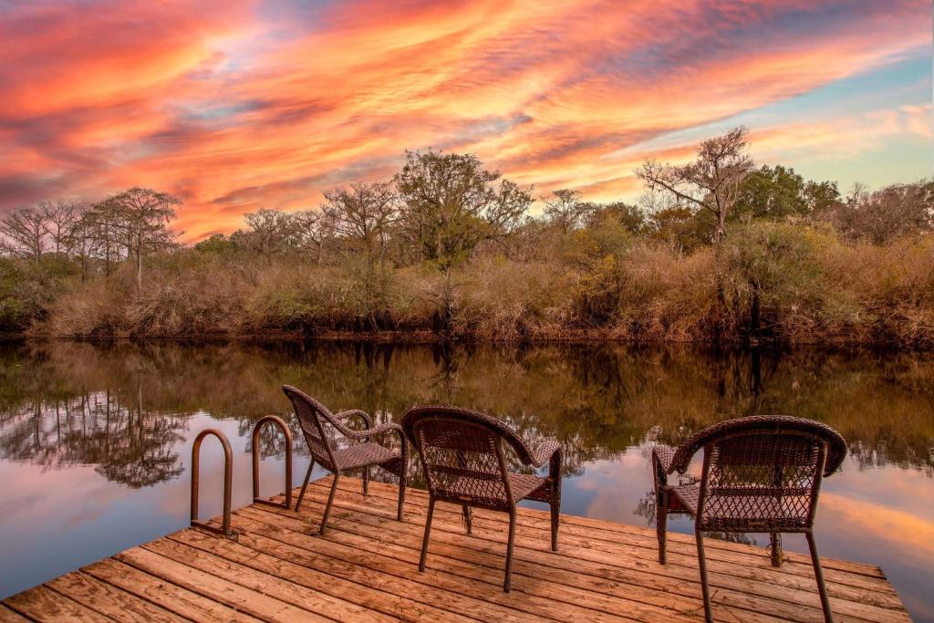 two chairs sitting on a dock on a body of water at Camp Manatee – Majestic Estate on Santa Fe River in Fort White