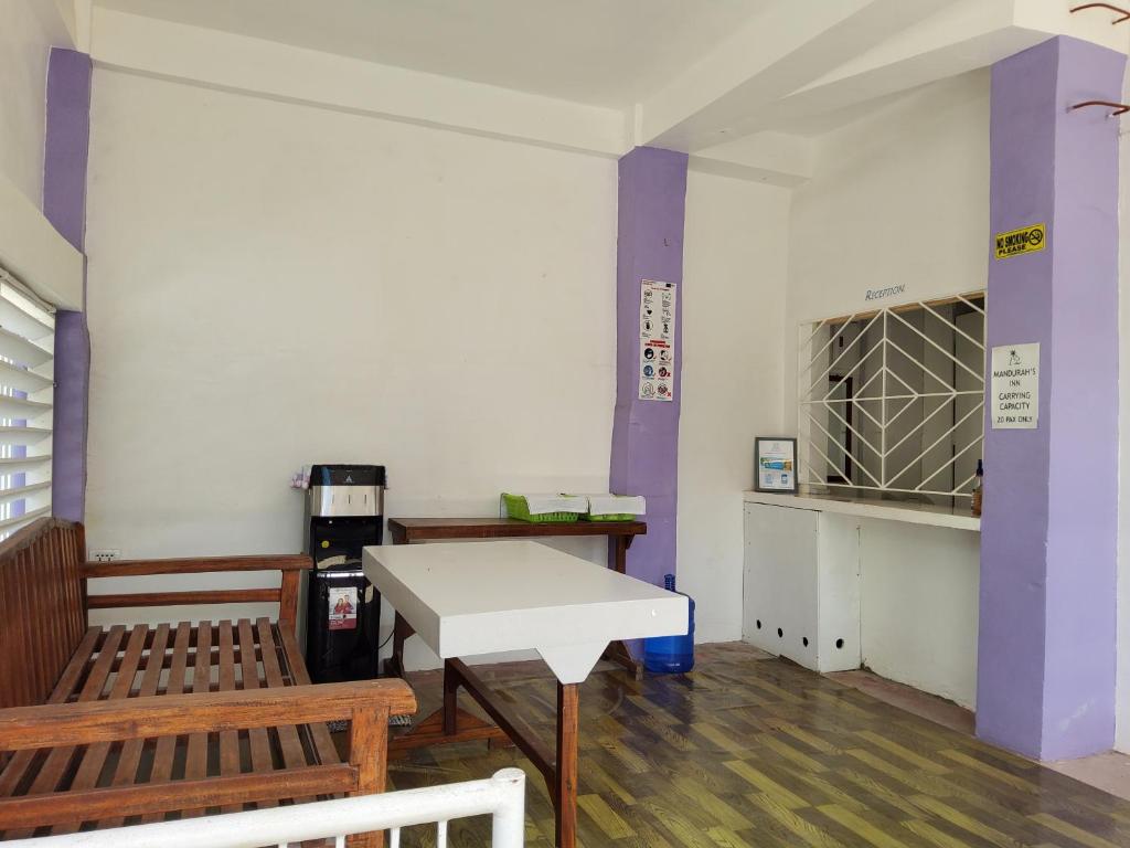 een kamer met twee banken en een tafel en paarse pilaren bij Mandurah's Inn, Malapascua in Malapascua Island