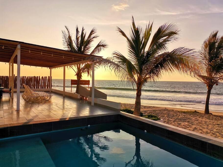 una piscina accanto a una spiaggia con palme di Casa de Playa Las Fragatas de Punta Mero a Canoas De Punta Sal
