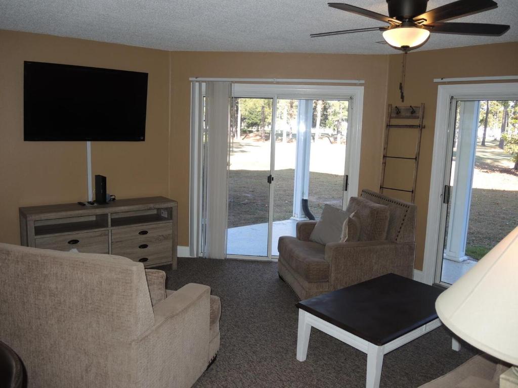sala de estar con sofá, sillas y TV de pantalla plana en Lake View Golf Resort Villa 1301, en Calabash