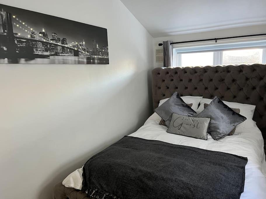 a bedroom with a bed with a black blanket and pillows at Glendale Gardens Apartment in Southend-on-Sea
