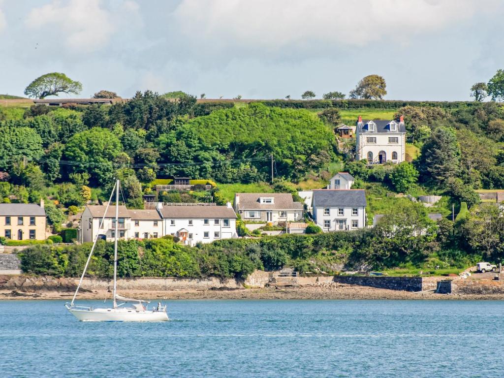 a sailboat in the water in front of houses at Haven View in Neyland