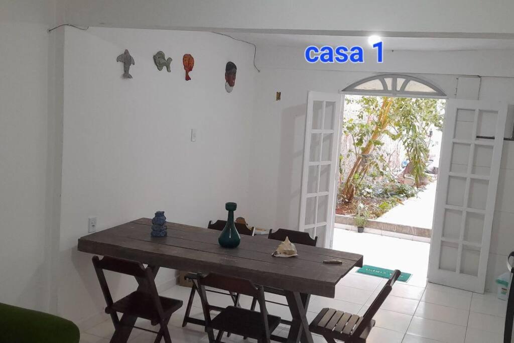 ein Esszimmer mit einem Tisch und Stühlen sowie einer offenen Tür in der Unterkunft Areia Branca Casas / casa 1. in Cabo Frio