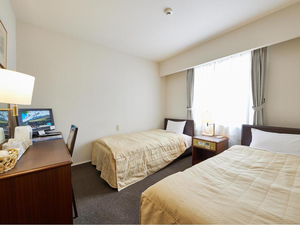 a hotel room with two beds and a television at Ichihara Marine Hotel in Ichihara